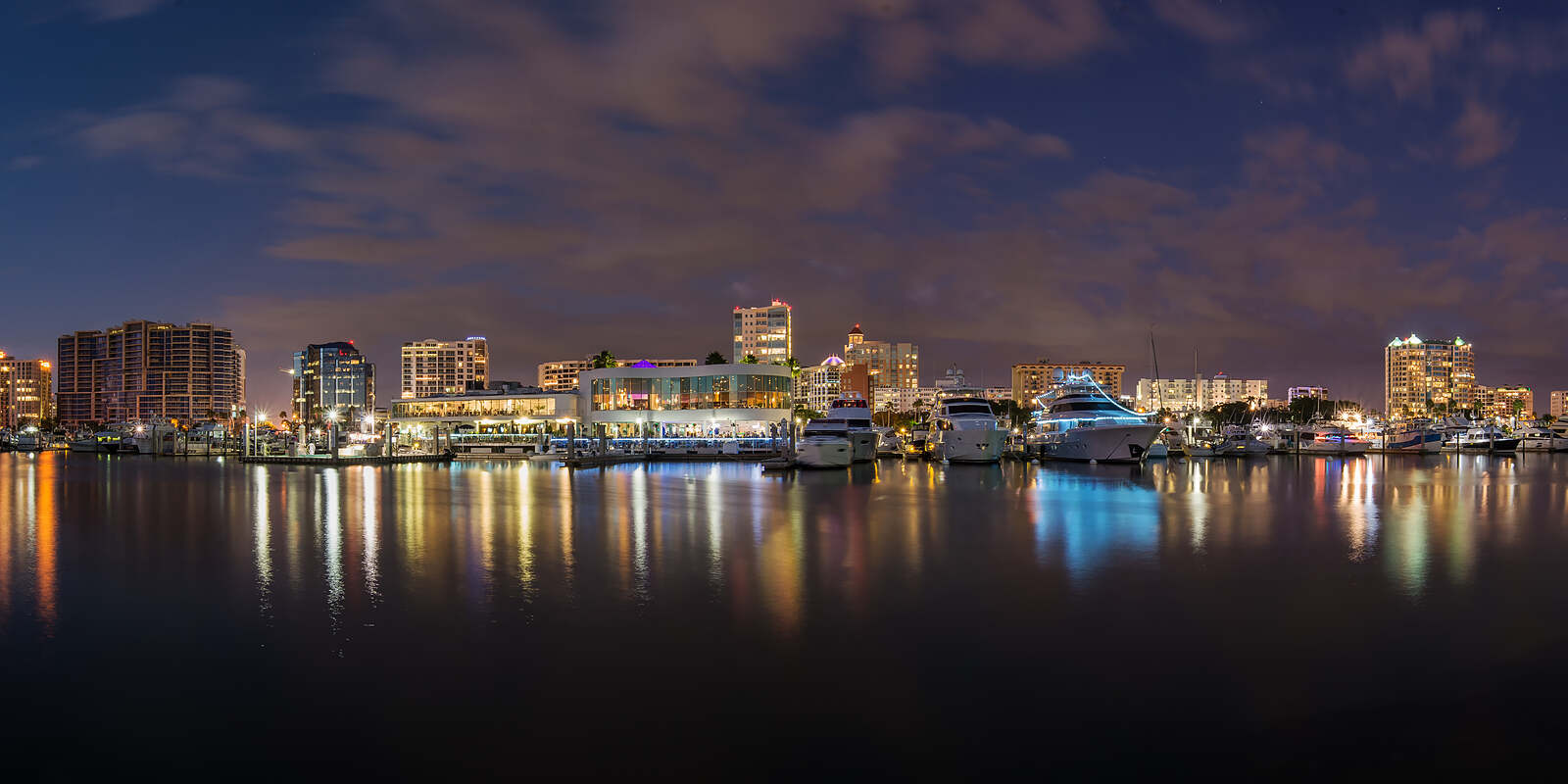 Downtown Sarasota's bayfront skyline and Marina Jack at night, reflected in Sarasota Bay.