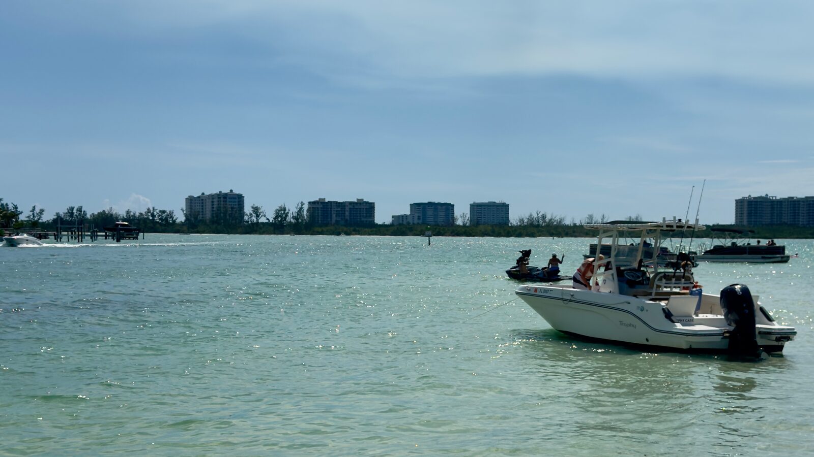 Boats anchored on a shallow turquoise sandbar in Sarasota Bay, with the Lido Key skyline on the horizon